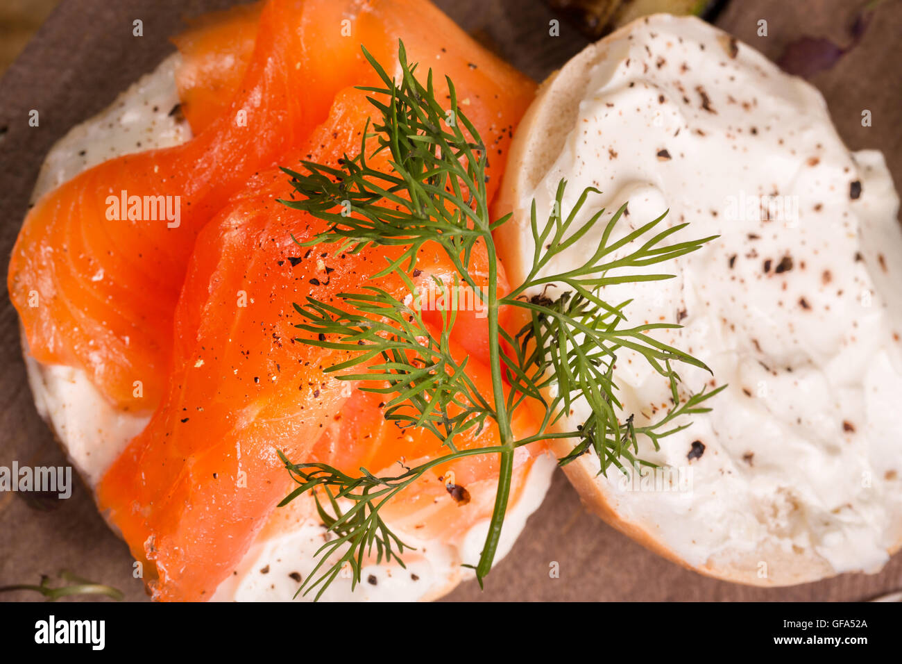 Smoked salmon and cream cheese on a bagel, with black pepper and a herb