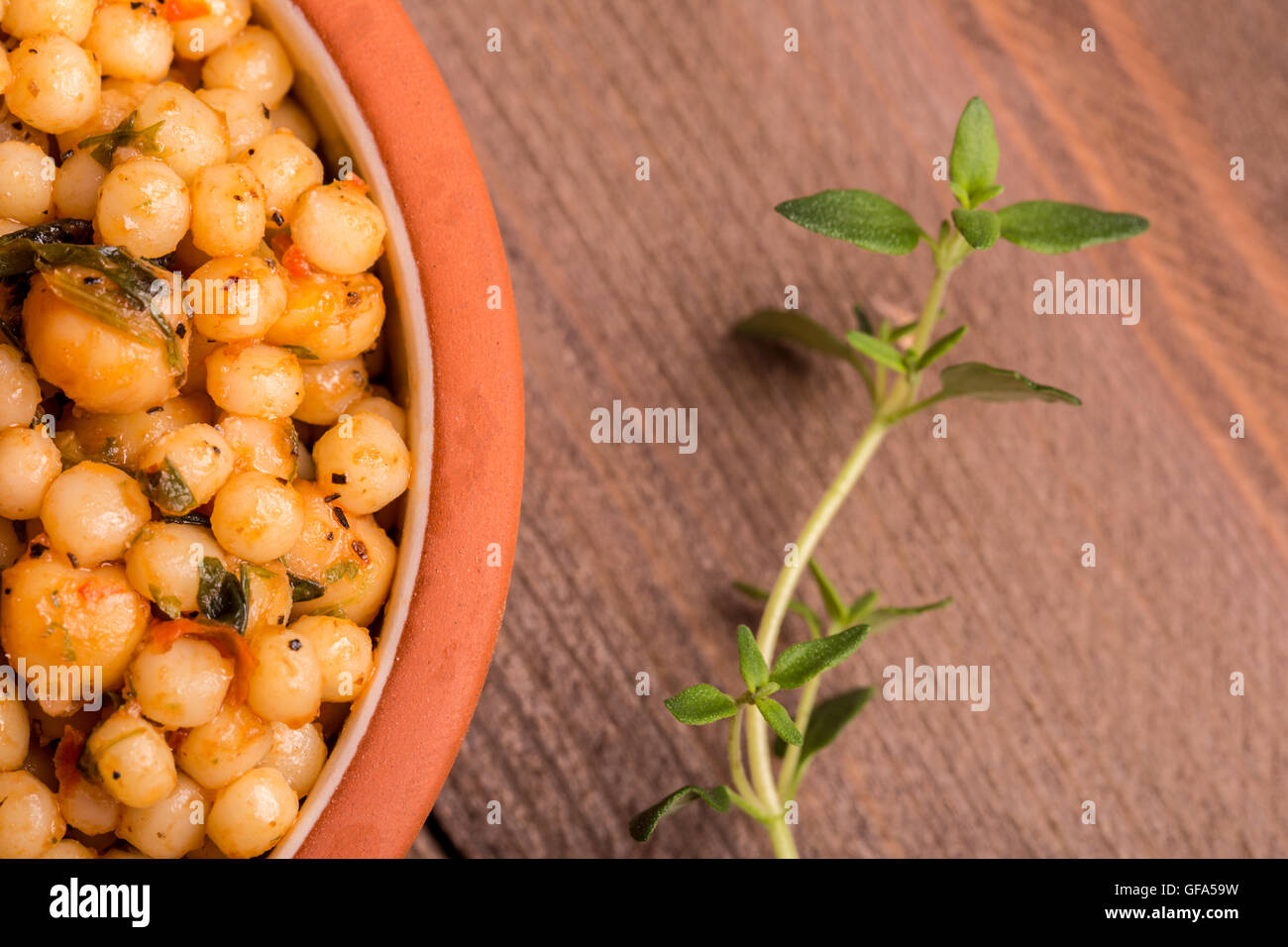 A tasty dish of chick peas with a strand of oregano next to it. Stock Photo