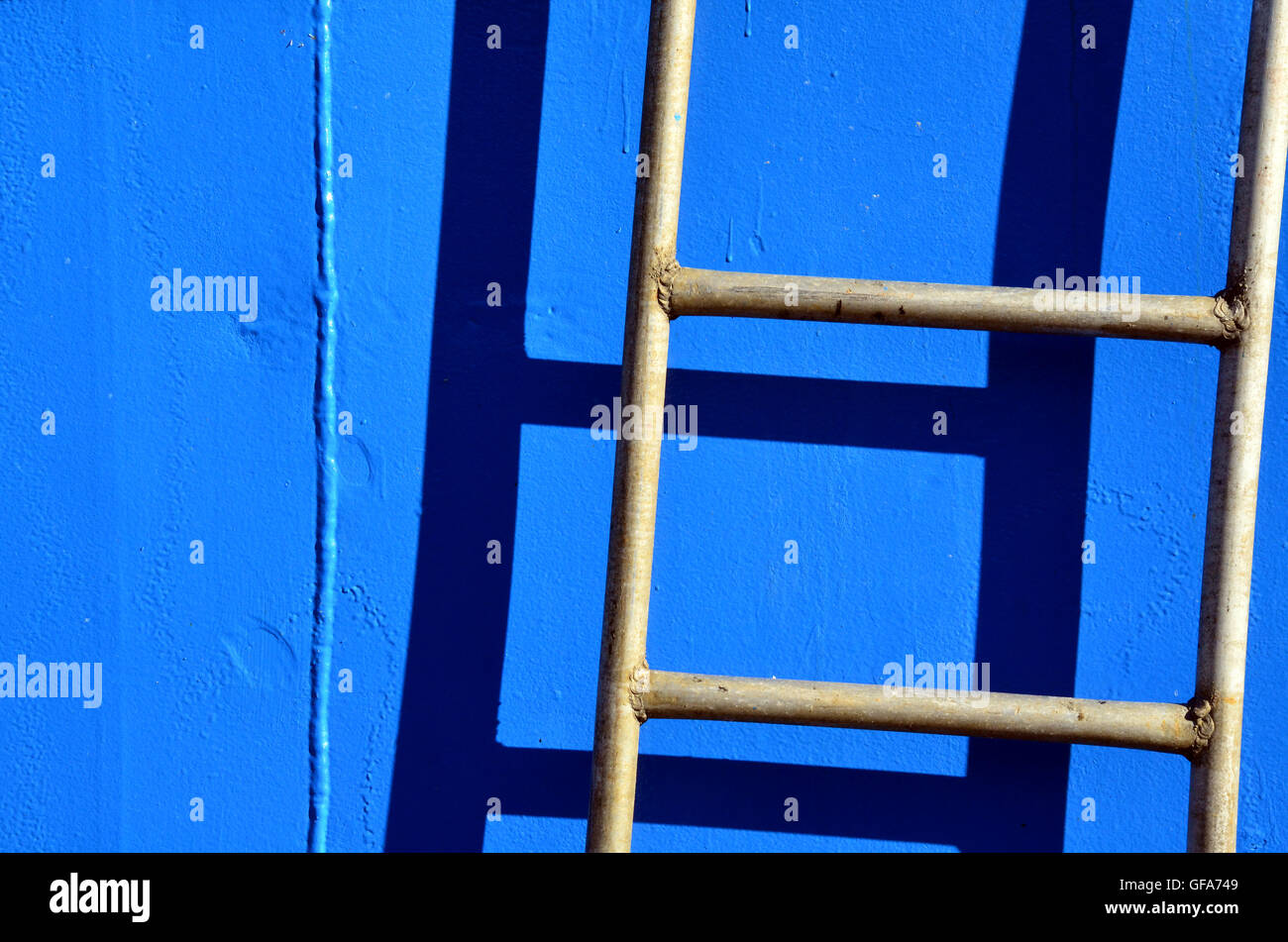 Closeup of ladder and its shadow on the blue side of a boat Stock Photo