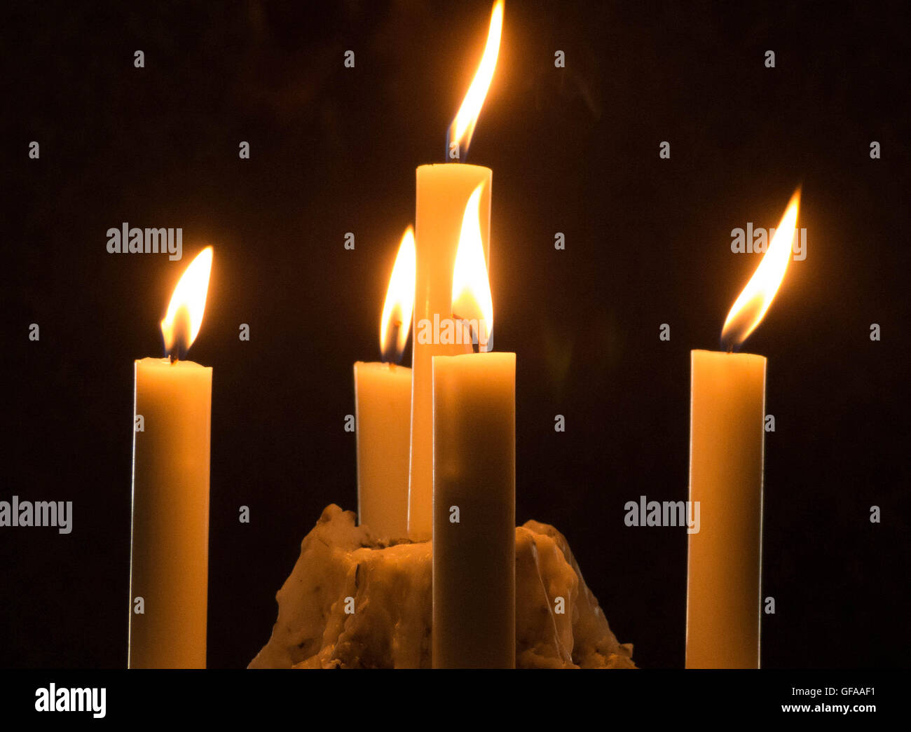 Candles lit on bed of wax Stock Photo Alamy
