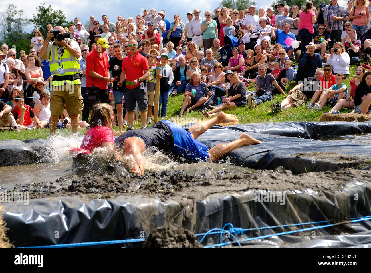 Lowland Games, Thorney, Somerset, UK, 31 July 2016: Competitors take part in the annual Lowland Games  “Wife Carrying” race in Somerset. Hundreds turned out in the heat to watch the Lowland Games which includes such events as a Raft Race, Hay Bale Racing , River its a Knock Out, Mud Wrestling, and Chunder Challenge. The games, originally started in 1984, are held annually in the Lowland village of Thorney which became flooded for the first time in centuries during the Somerset floods in January 2014. Stock Photo