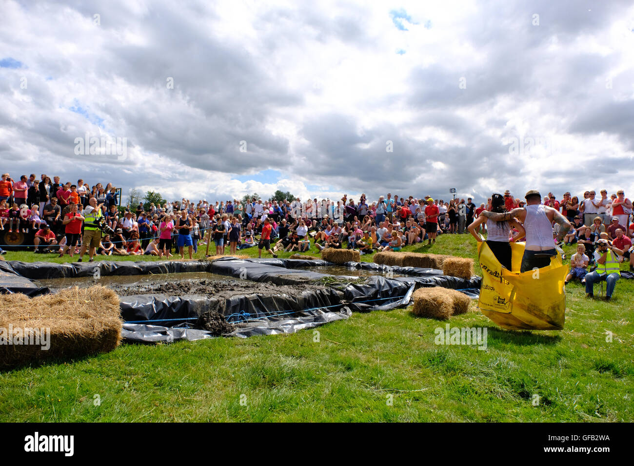 Lowland Games, Thorney, Somerset, UK, 31 July 2016: Competitors take part in the annual Lowland Games  “Wife Carrying” race in Somerset. Hundreds turned out in the heat to watch the Lowland Games which includes such events as a Raft Race, Hay Bale Racing , River its a Knock Out, Mud Wrestling, and Chunder Challenge. The games, originally started in 1984, are held annually in the Lowland village of Thorney . Stock Photo