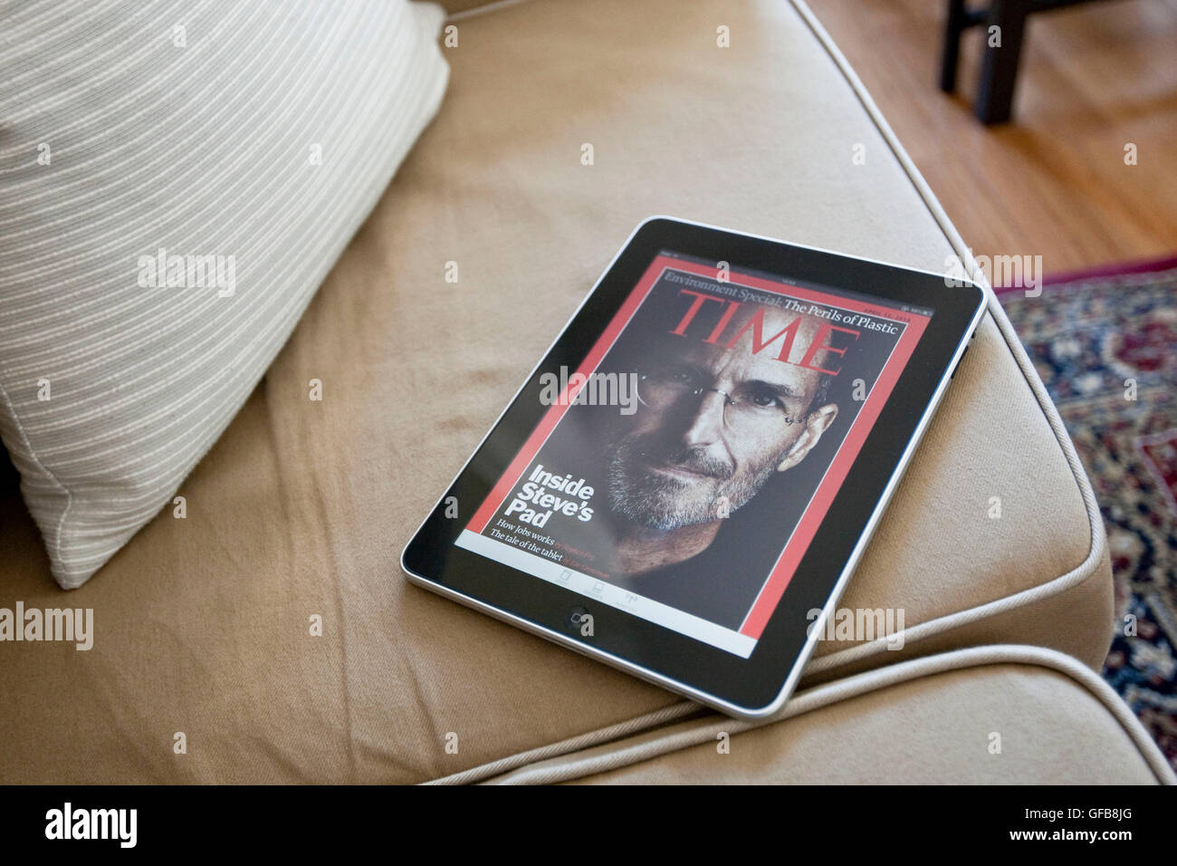 Apple iPad on an apartment sofa displaying the Time Magazine application with Steve Jobs on the cover, 2010. Stock Photo