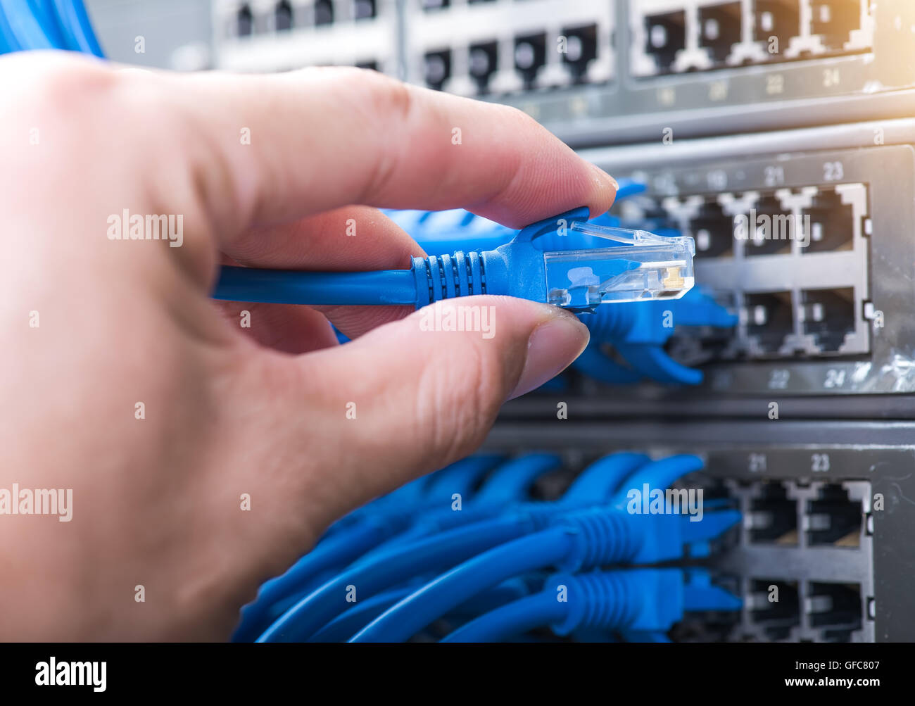 man working in network server room with fiber optic hub for digital ...