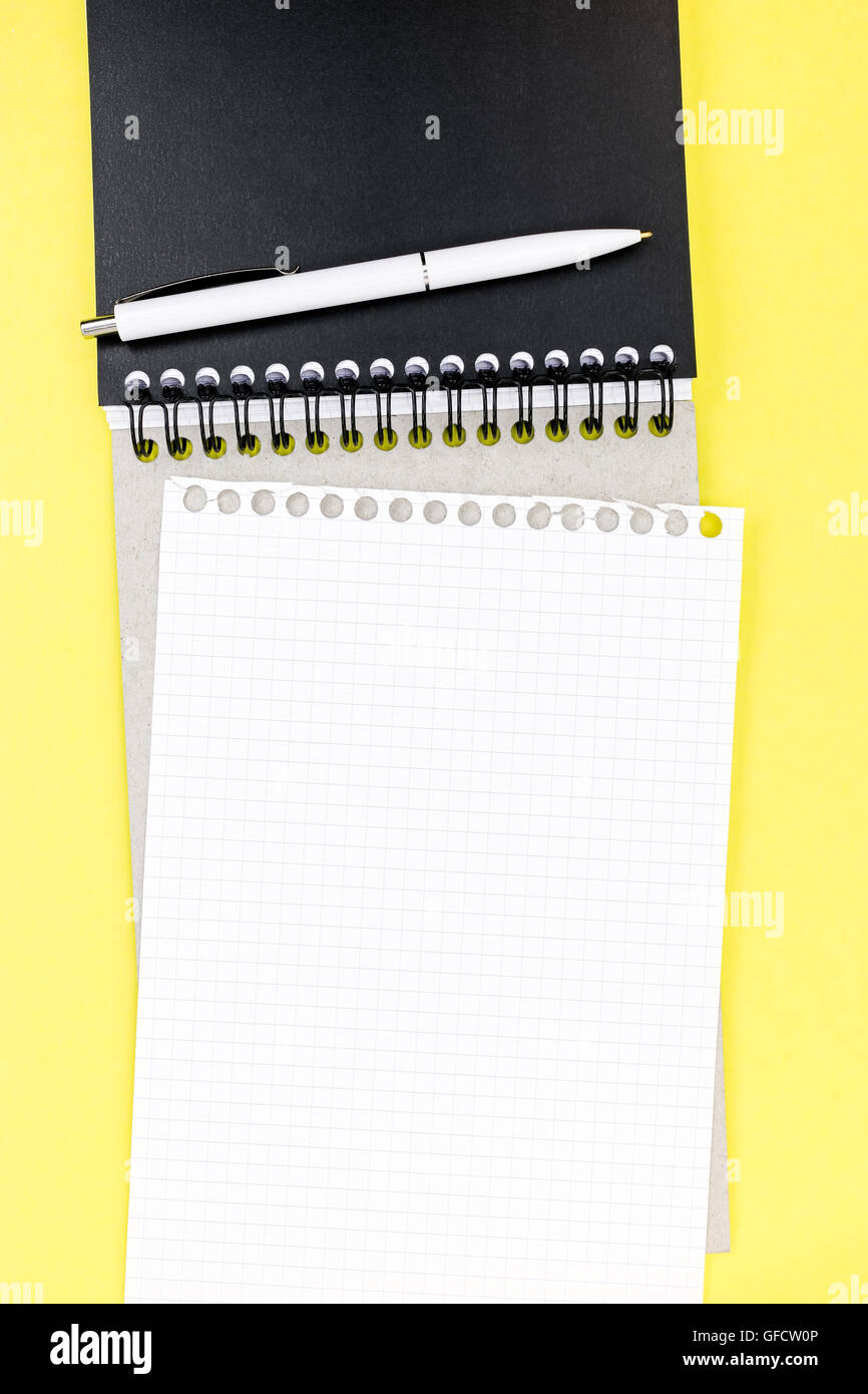 notebook with piece of white clean squared paper on yellow table background Stock Photo