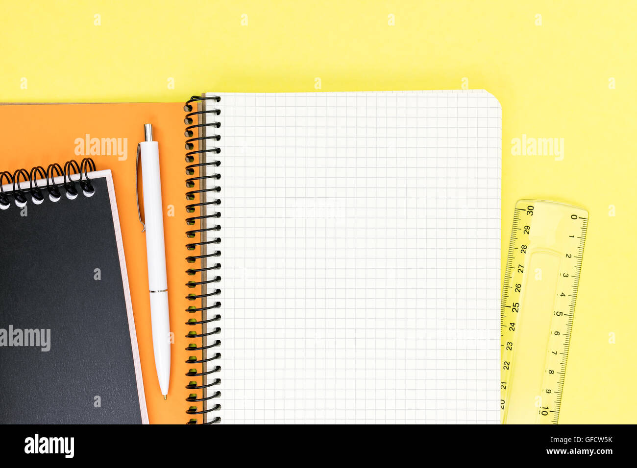 notepads with open clean squared page with ruler and pencil on yellow desktop background Stock Photo