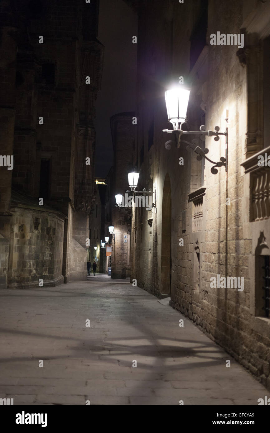 Narrow alley illuminated by street lamps at night, Barcelona, Catalonia ...