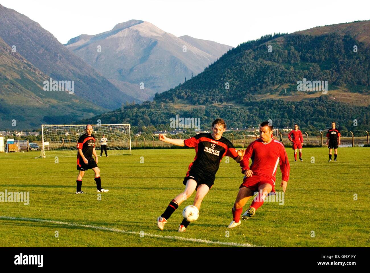 Local football teams Ballachulish and Buckfast play on pitch at Fort William below entrance to Glen Nevis. Highland, Scotland Stock Photo