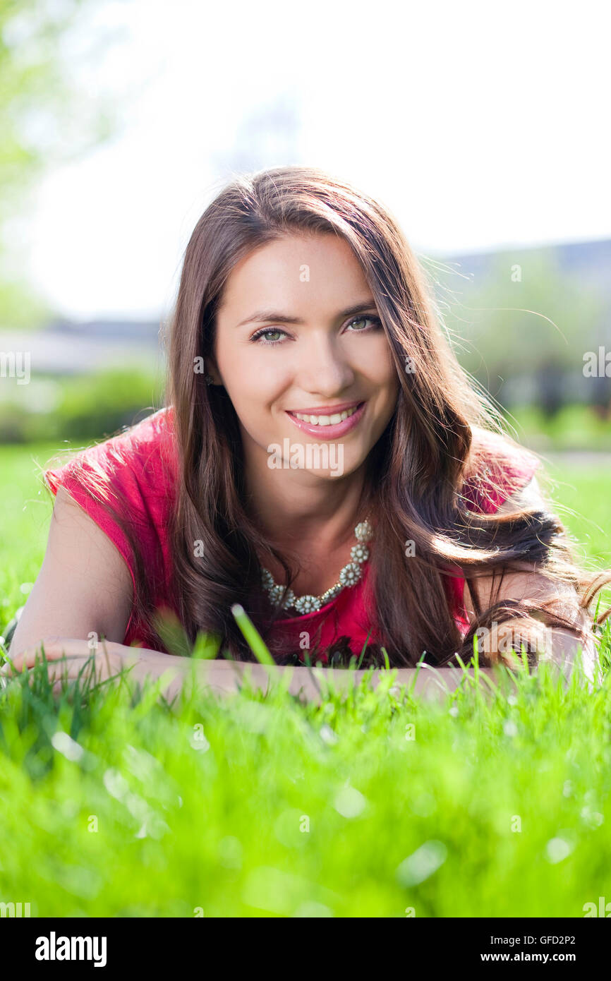 Portrait of young woman lying on a green lawn Stock Photo - Alamy