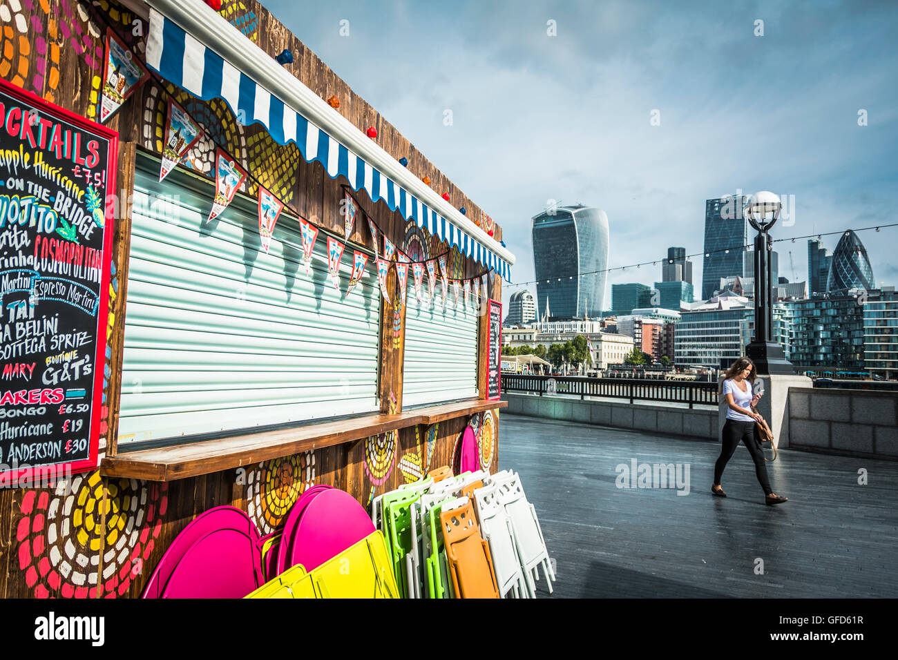 A young woman walks past a brightly coloured cocktail bar next to the river Thames on Queen's Walk, London, SE1, UK Stock Photo