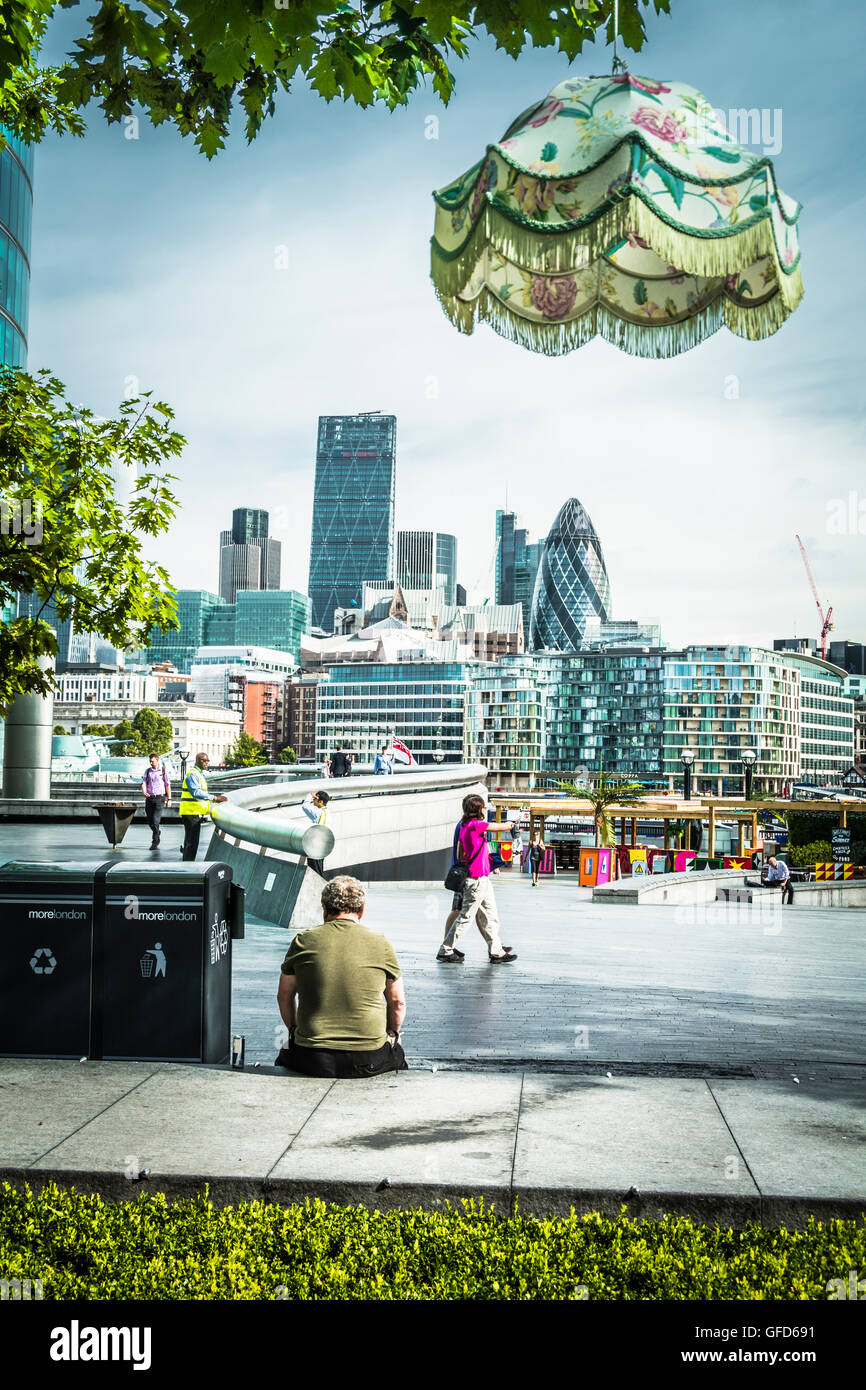 A pretty lampshade sits atop the Gherkin as seen from More London in the Scoop, Queen's Walk, London SE1 Stock Photo