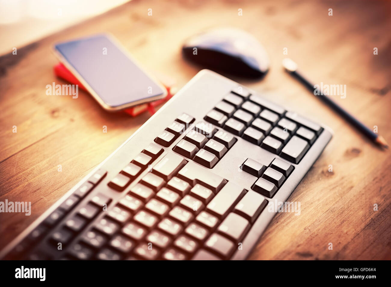 Desktop in the office, computer keyboard, pc mouse and mobile phone on the wooden table, work place of somebody Stock Photo