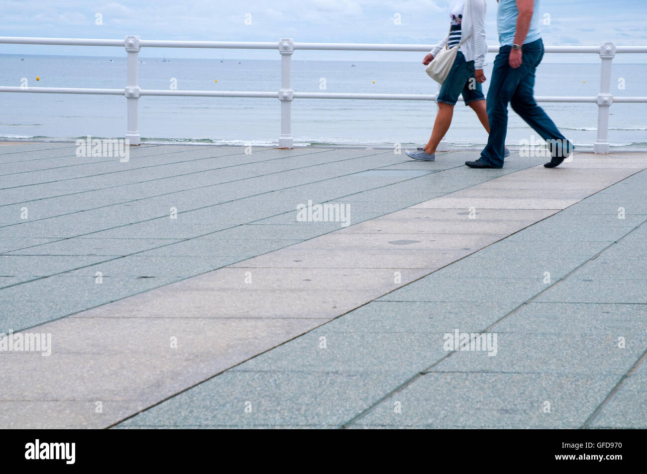 Couple walking along the promenade. Gijon, Asturias, Spain. Stock Photo