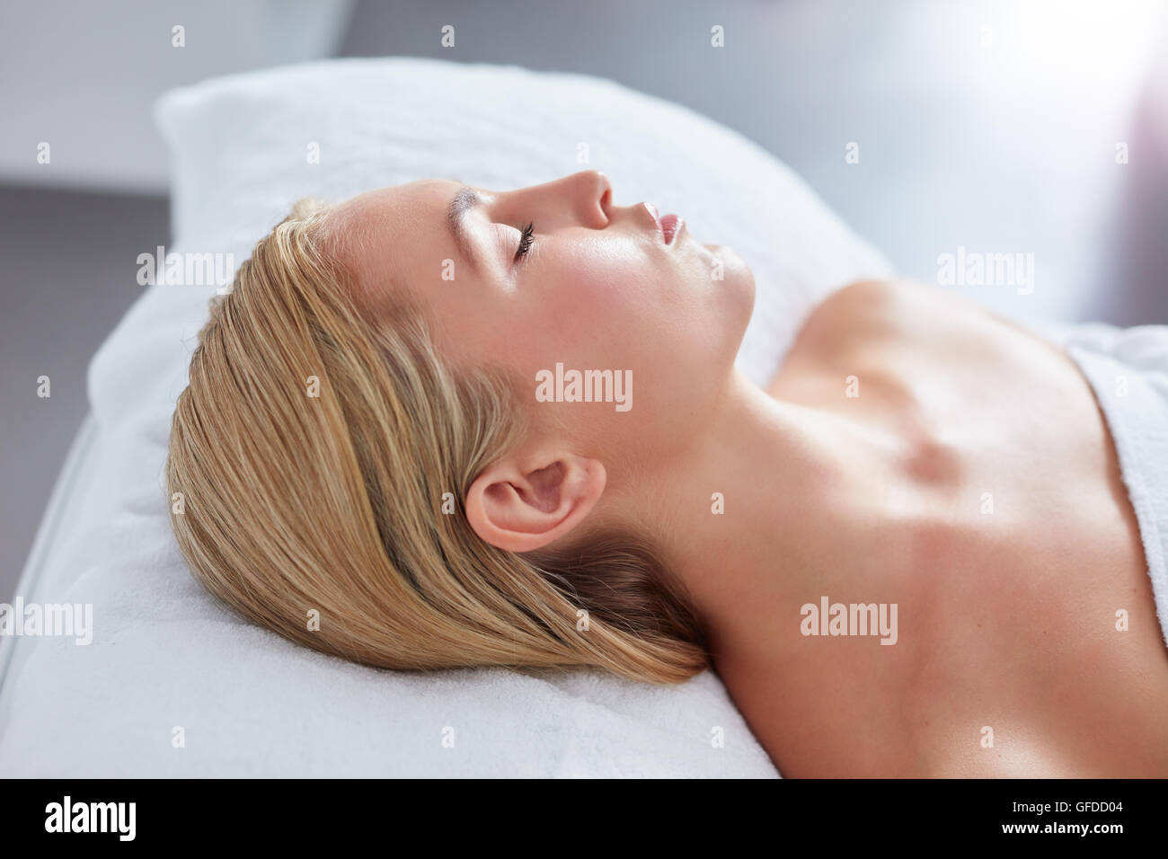 Close up shot of young woman relaxing on massage table. She lying with her eyes closed waiting for the spa treatment, with focus Stock Photo