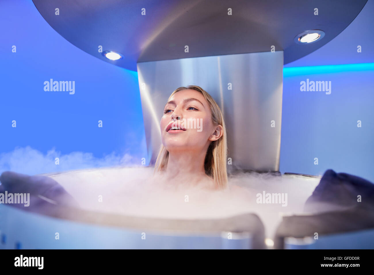 Portrait of young woman in a whole body cryotherapy chamber. Female getting cryo therapy at the cosmetology clinic. Stock Photo