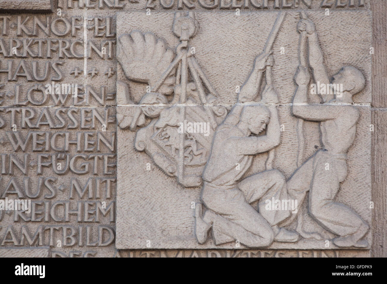 Workers install the coat of arms of Dresden on the building of the Neues Rathaus (New City Hall). Detail of the GDR-time relief dedicated to city history at the Altmarkt (Old Market Square) in Dresden, Saxony, Germany. Stock Photo
