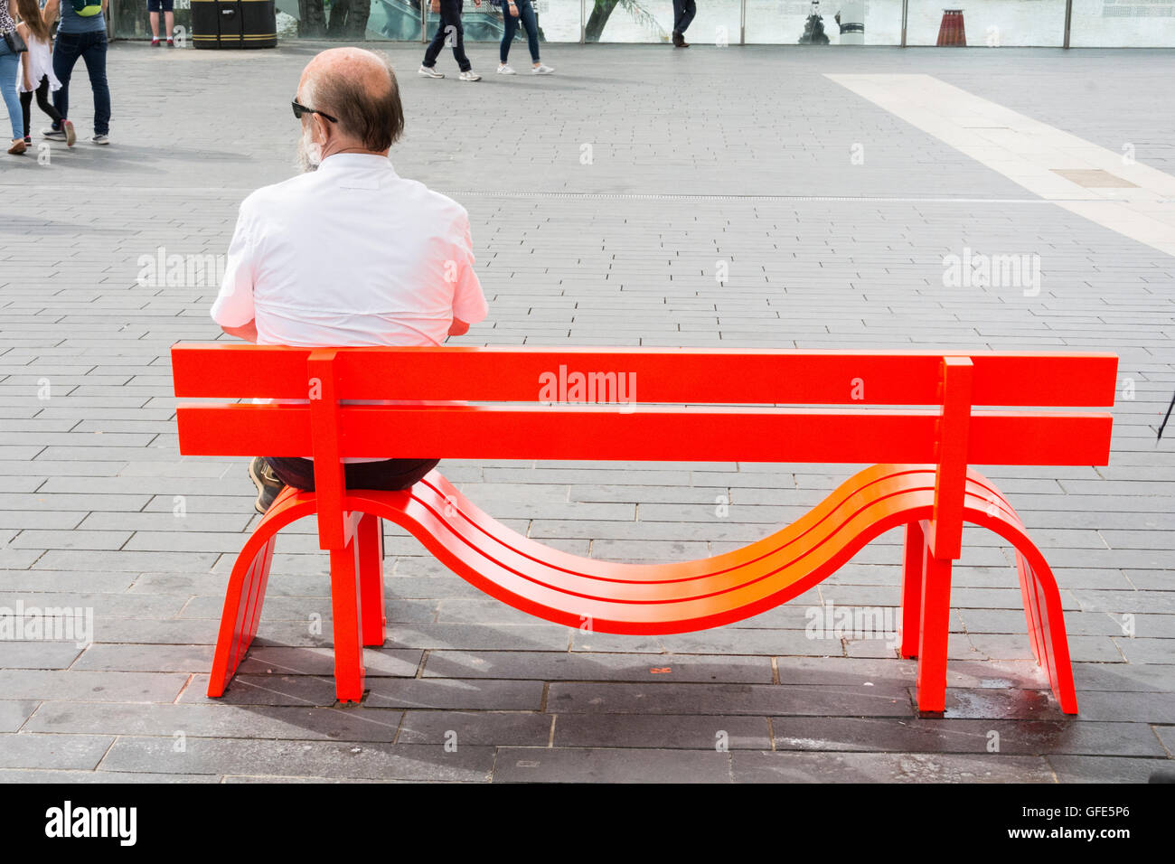 A middle-aged man sitting on one of Jeppe Hein's Modified Social Benches on London's South Bank, SE1, UK Stock Photo