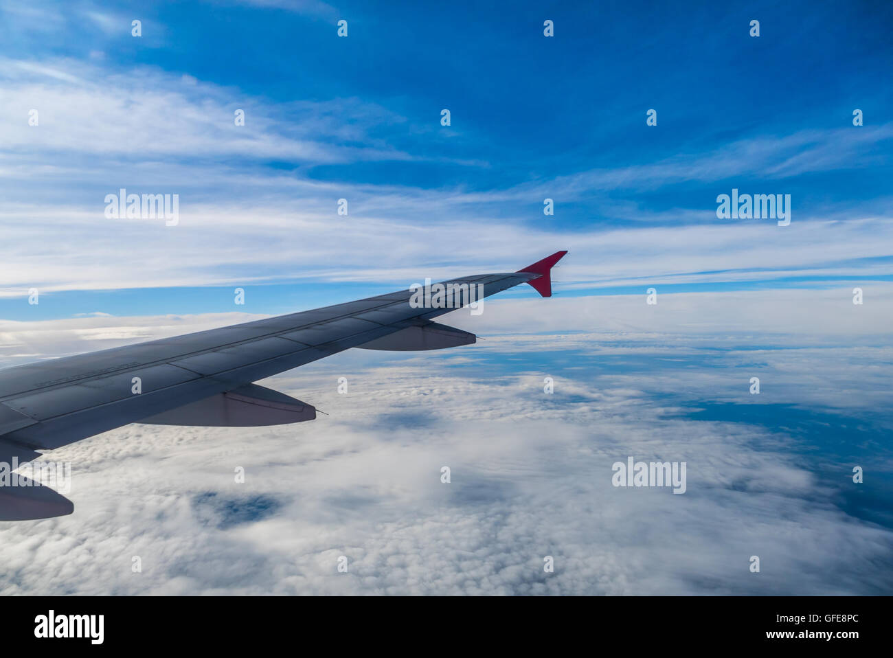 Airplane flying above clouds at sunrise filter Stock Photo