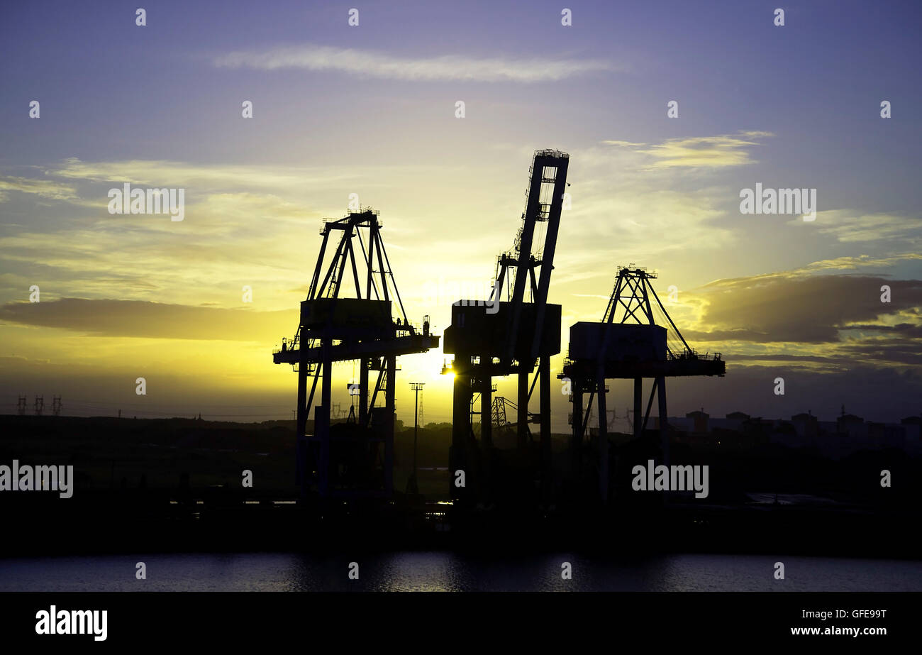 Cranes lit up by the bright night sky at Dunkirk Port waterside Stock Photo