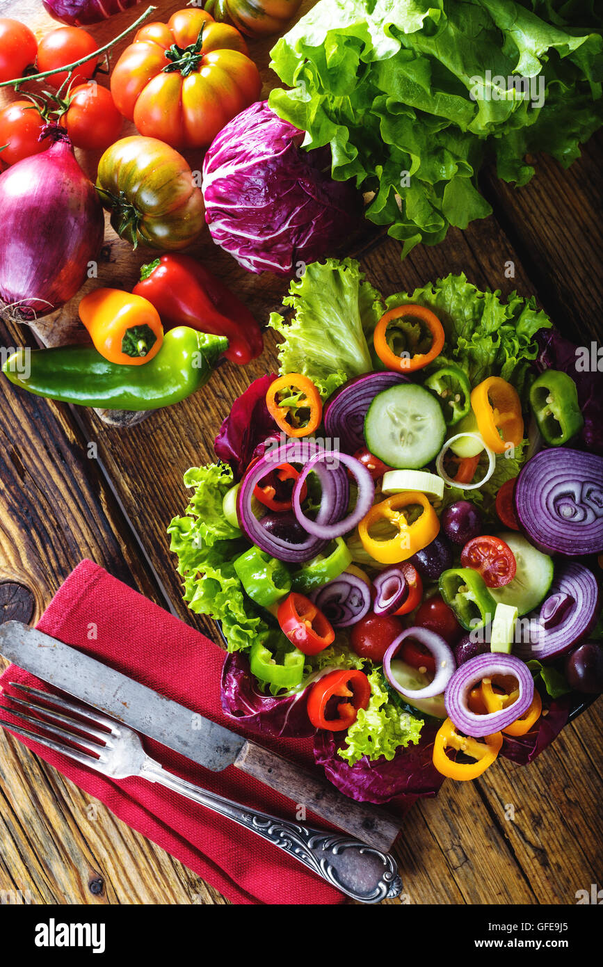 Spring salad with fresh juicy vegetables on a rustic wooden table. Stock Photo