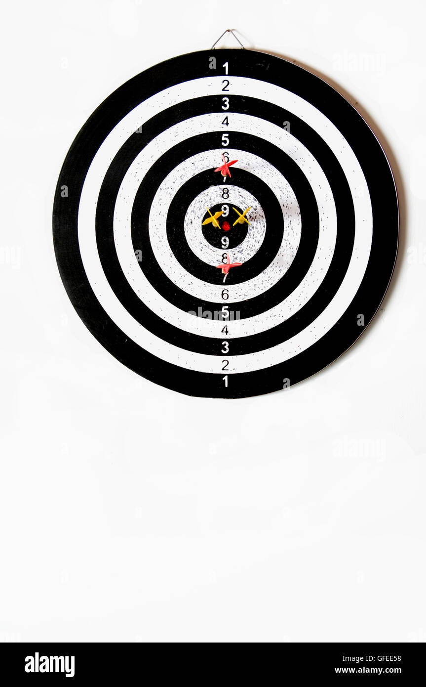 Dart board on white background with 2 yellow and two red darts around the centre Stock Photo