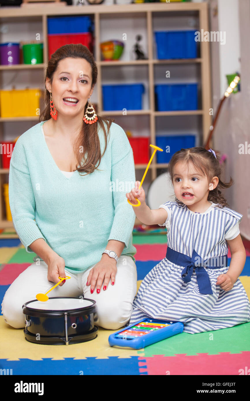 Little girl playing musical instruments with her Mom Stock Photo