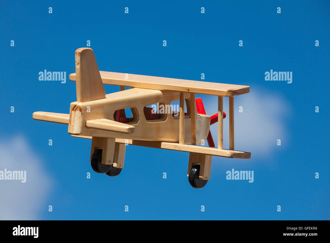 Wooden Plane flying with blue sky and white clouds - Going away Stock Photo