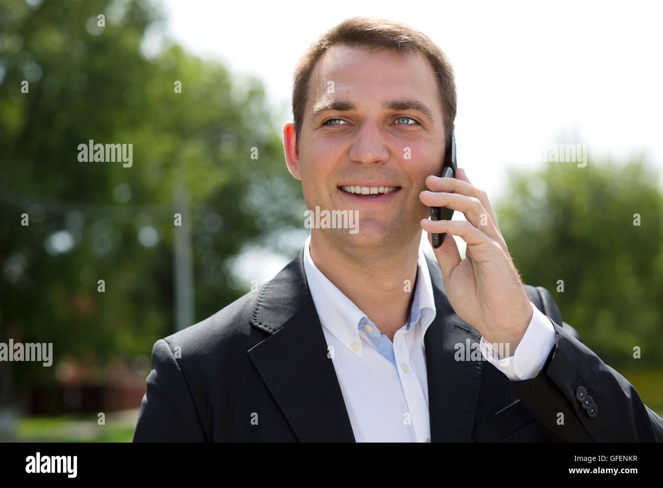 Young urban professional man talking on smartphone. Close up portrait of male business man on smart phone outdoors in suit jacke Stock Photo