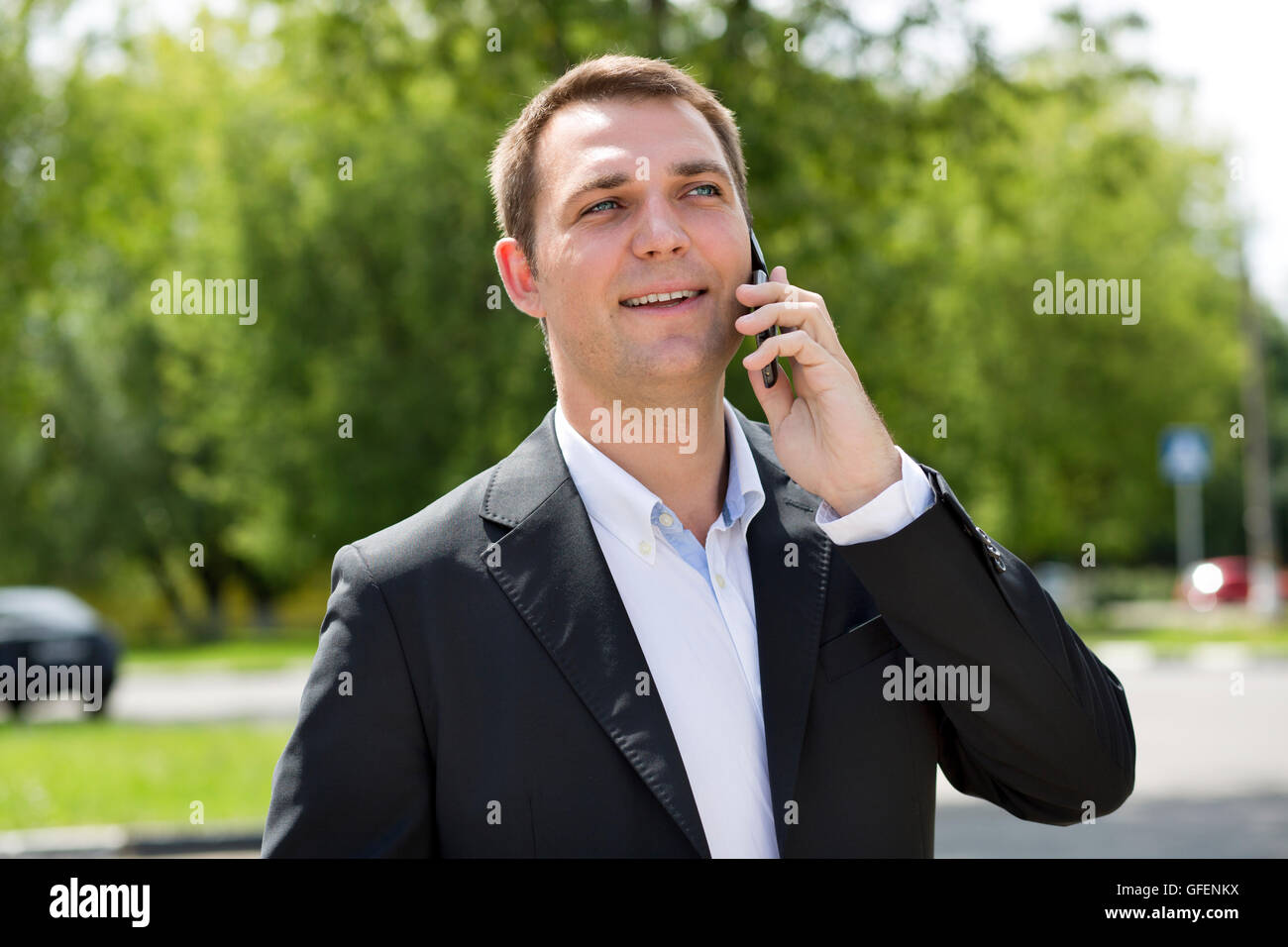 Young urban professional man talking on smart phone. Close up portrait of male business man on smart phone outdoors in suit Stock Photo