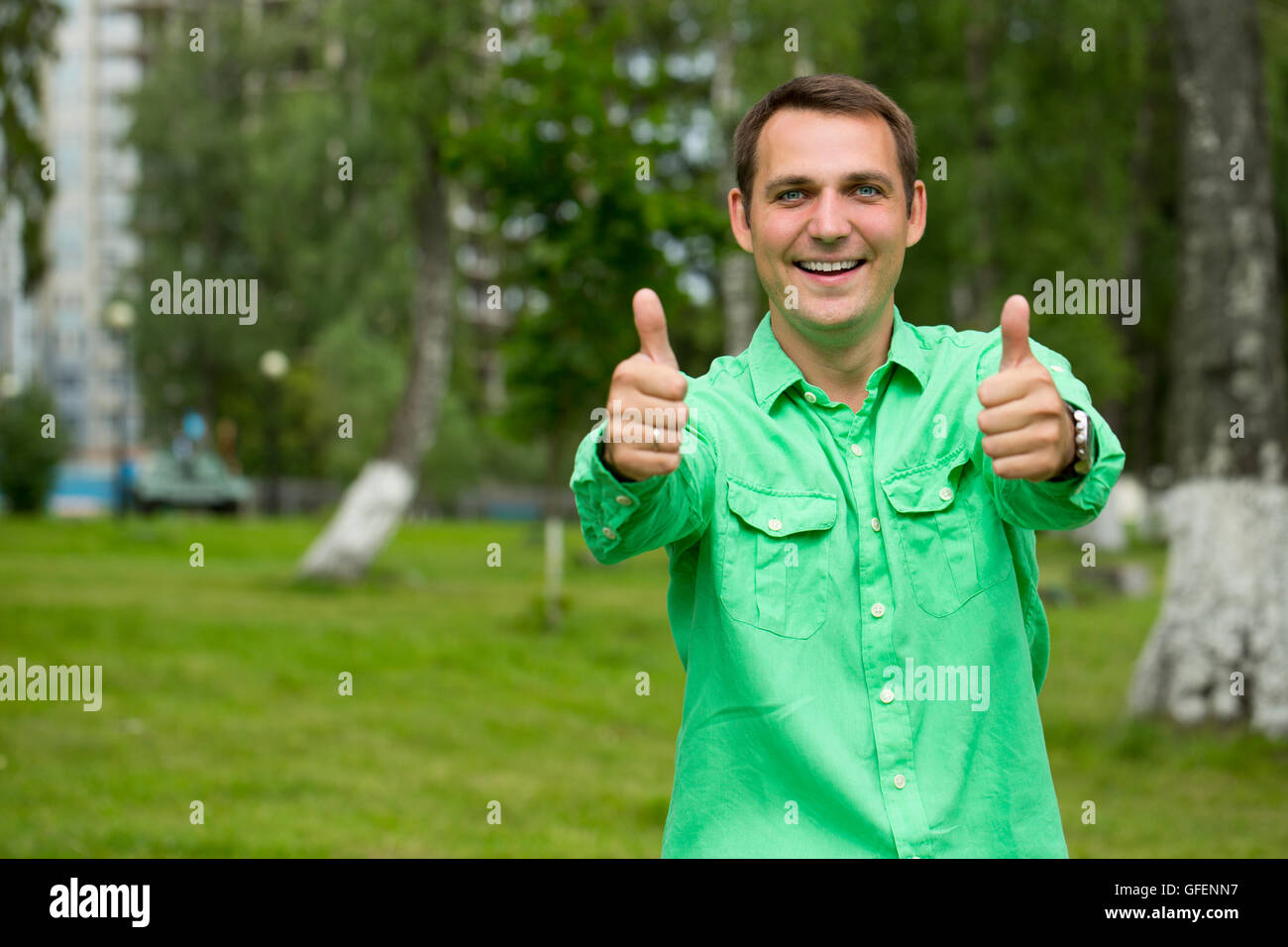 Portrait of a young handsome man with thumb up in a green shirt on the ...