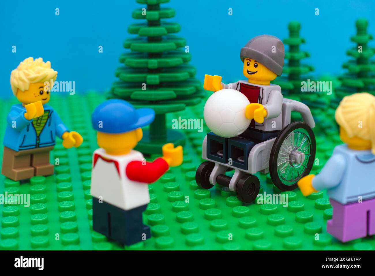 Tambov, Russian Federation - July 30, 2016 Lego boy in wheelchair playing ball with his friends in park. Studio shot. Stock Photo