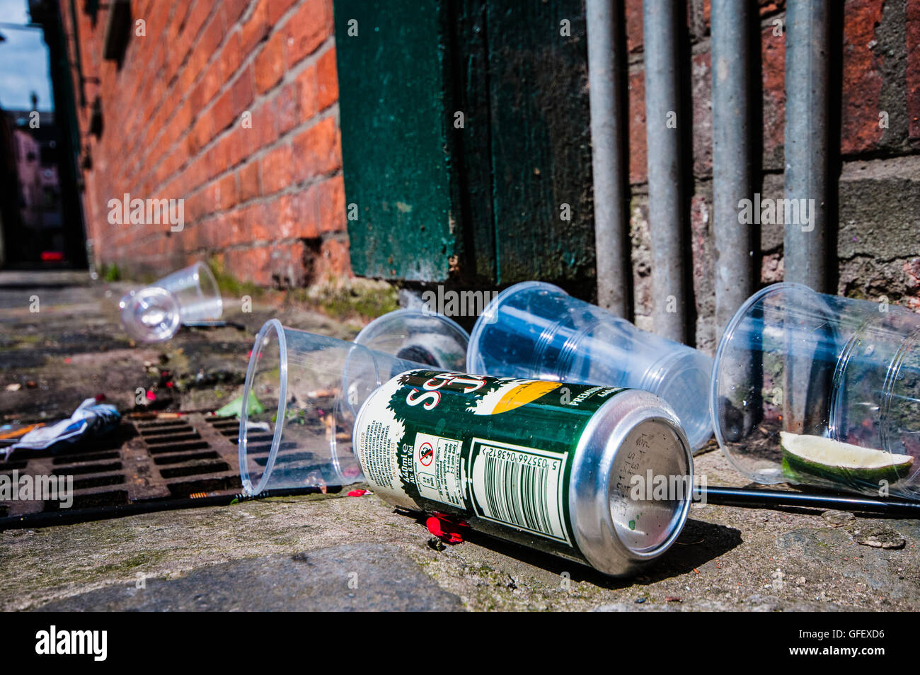Empty plastic pint glasses and a tin of scrumpy cider littering a city street Stock Photo