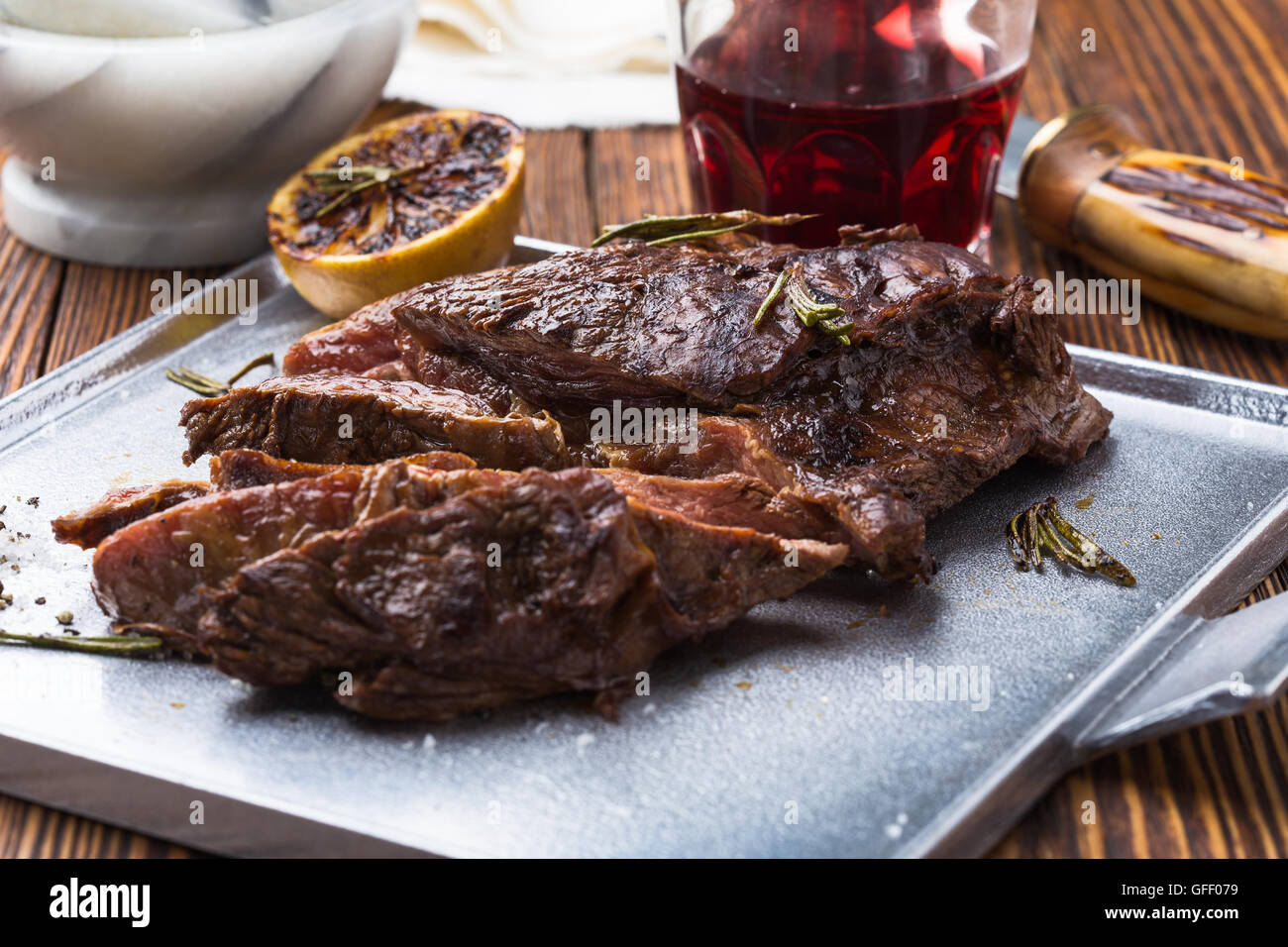 Medium rare grilled marinated beef flank steak on silver plate Stock