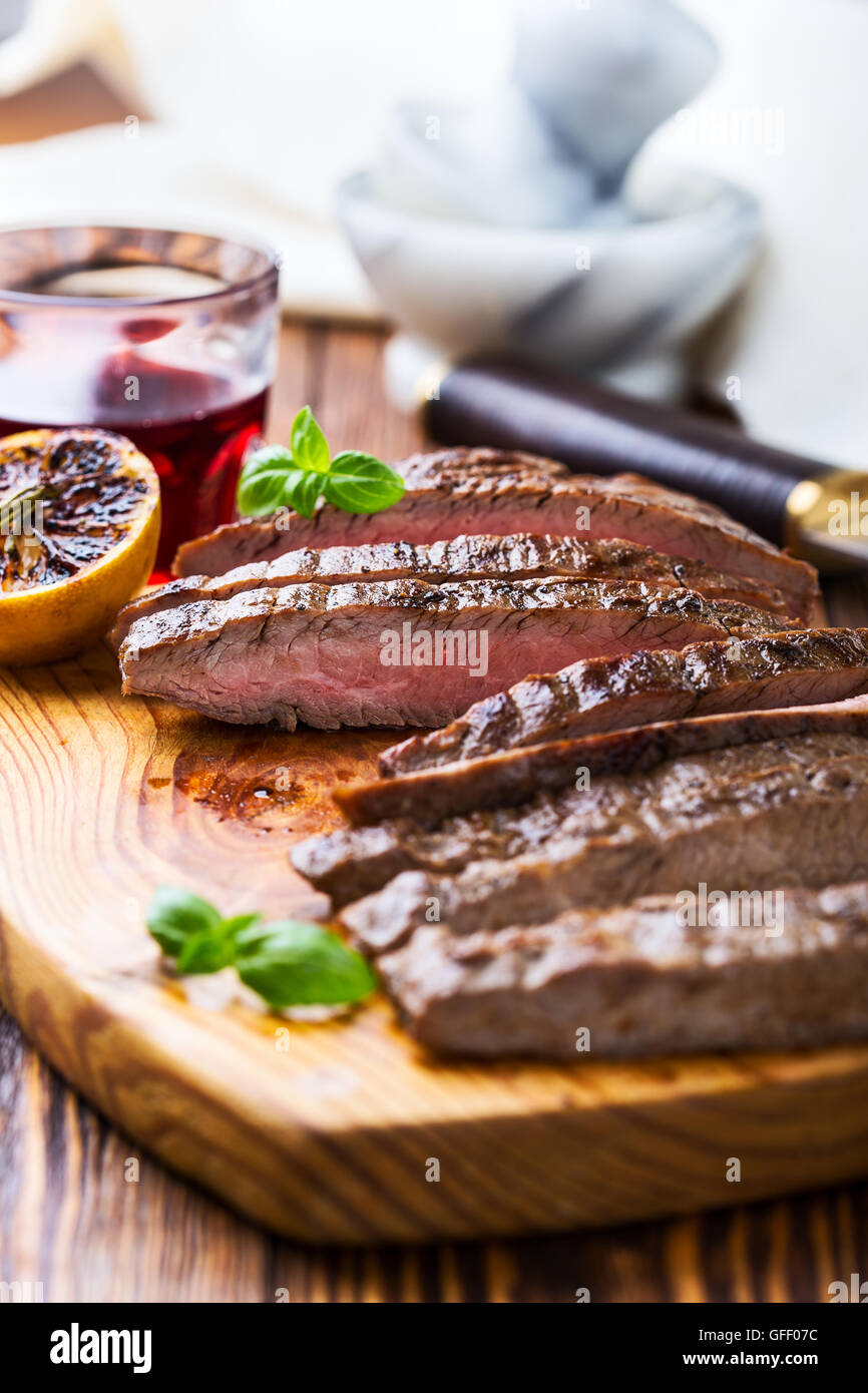 Welldone grilled marinated beef flank steak on wooden board Stock