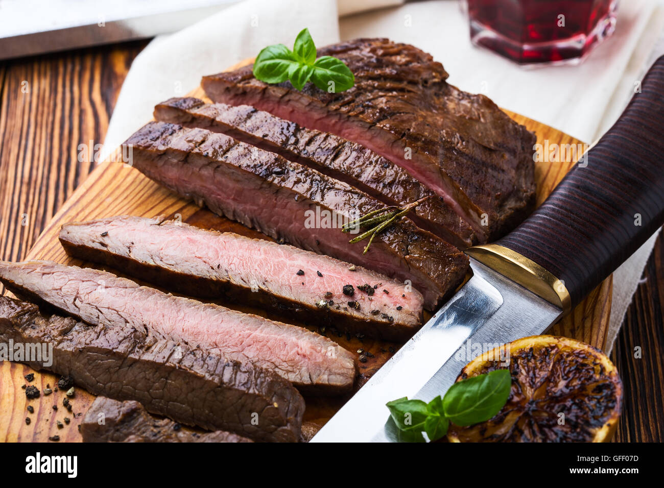 Welldone grilled marinated beef flank steak on wooden board Stock