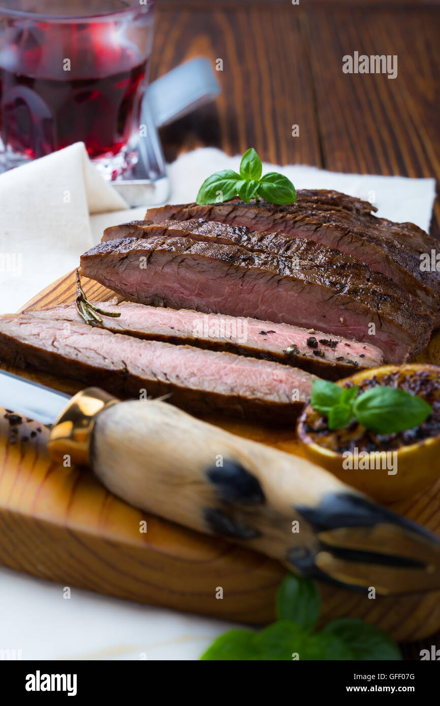 Welldone grilled marinated beef flank steak on wooden board Stock