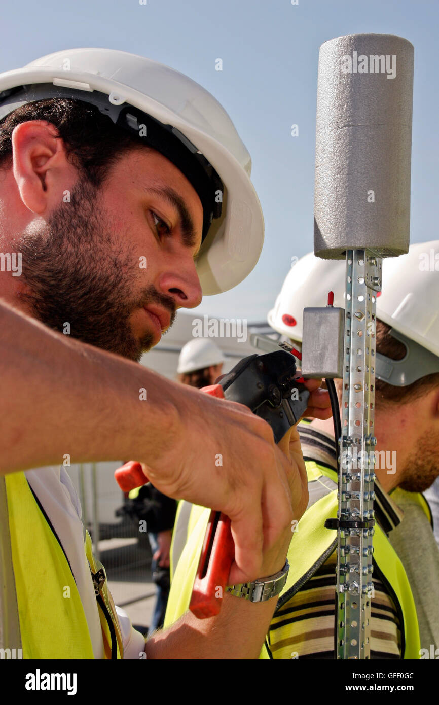 Electrician worker, with hard hat, using wire cutters. England, United