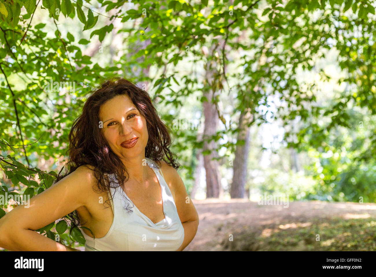 Close Up Of Busty Classy Mature Woman Smiling At The Camera Against Green Garden Background With