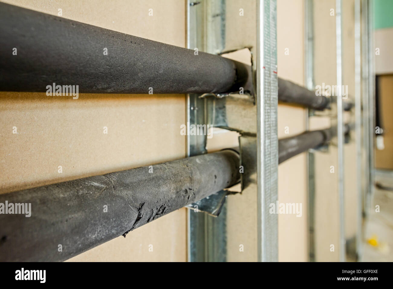 View at unfinished thermal partition dry wall with water pipeline going through metal profiles. Stock Photo