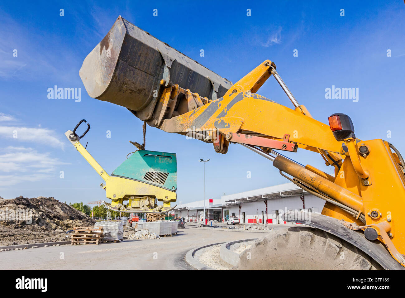 Excavator is moving over building site with raised up front bucket