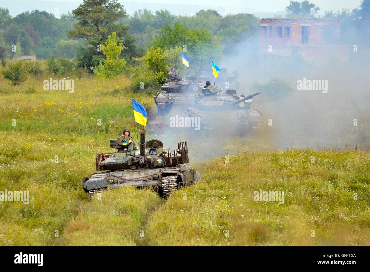 Main battle tanks under the Ukrainian flags at a firing range in summer
