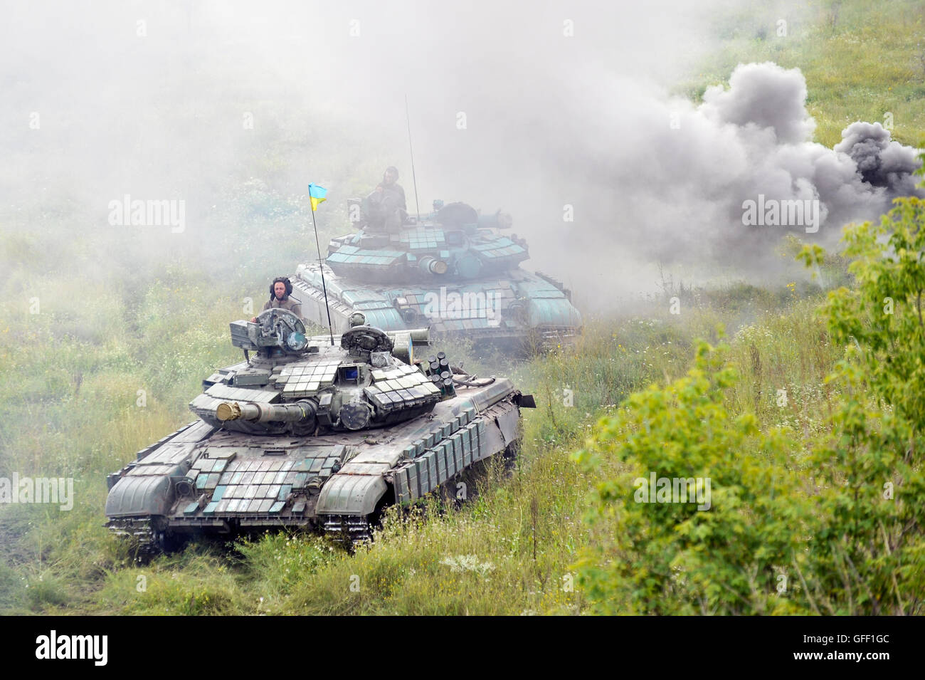 Main battle tanks under the Ukrainian flags at a firing range in summer