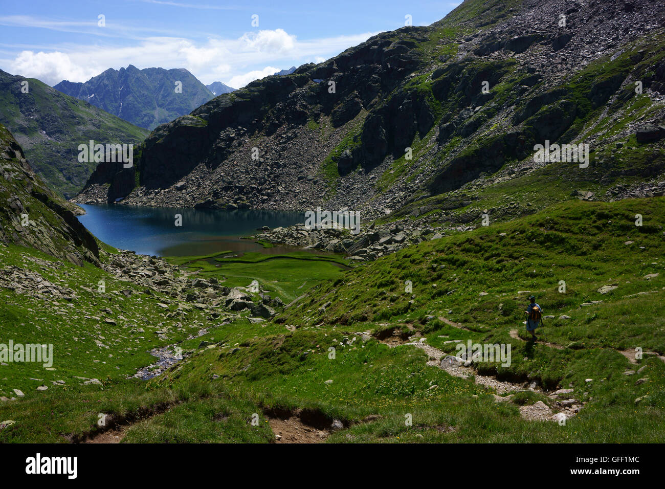 Hiker descending toward Toma lake, Leigh da Tuma, source of Rhine river, Grisons, Switzerland Stock Photo