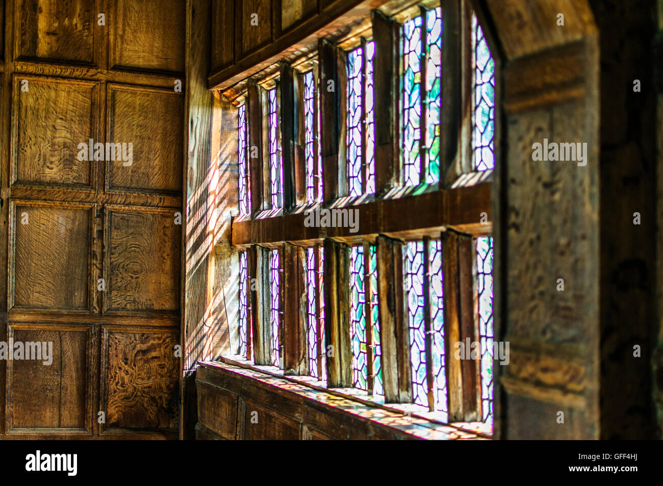 Stained glass window in Morton Hall. Light coming through on to wooden panals Stock Photo