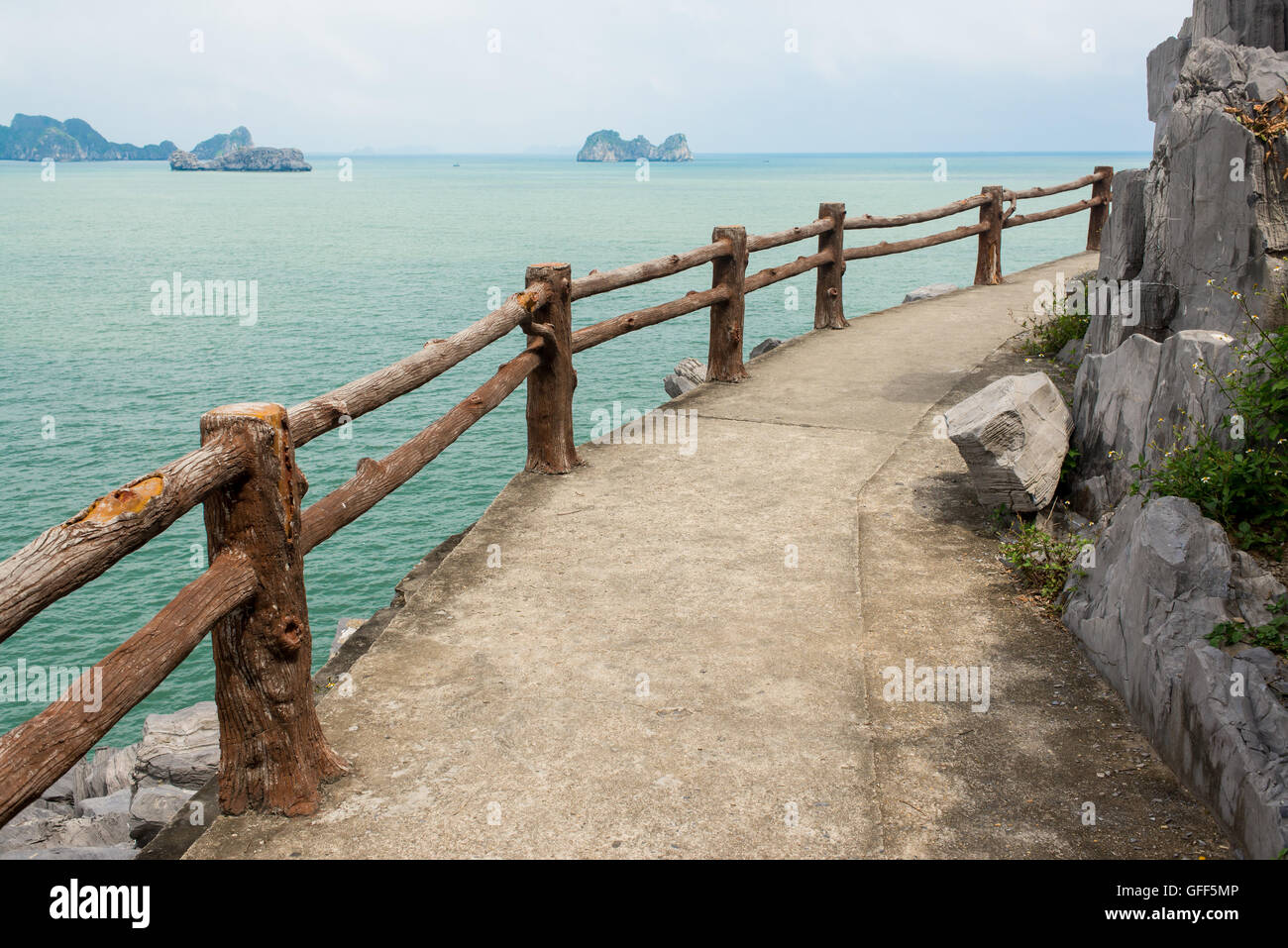 Empty path with wooden fence on a cliff facing the open sea with small islands in the distance Stock Photo