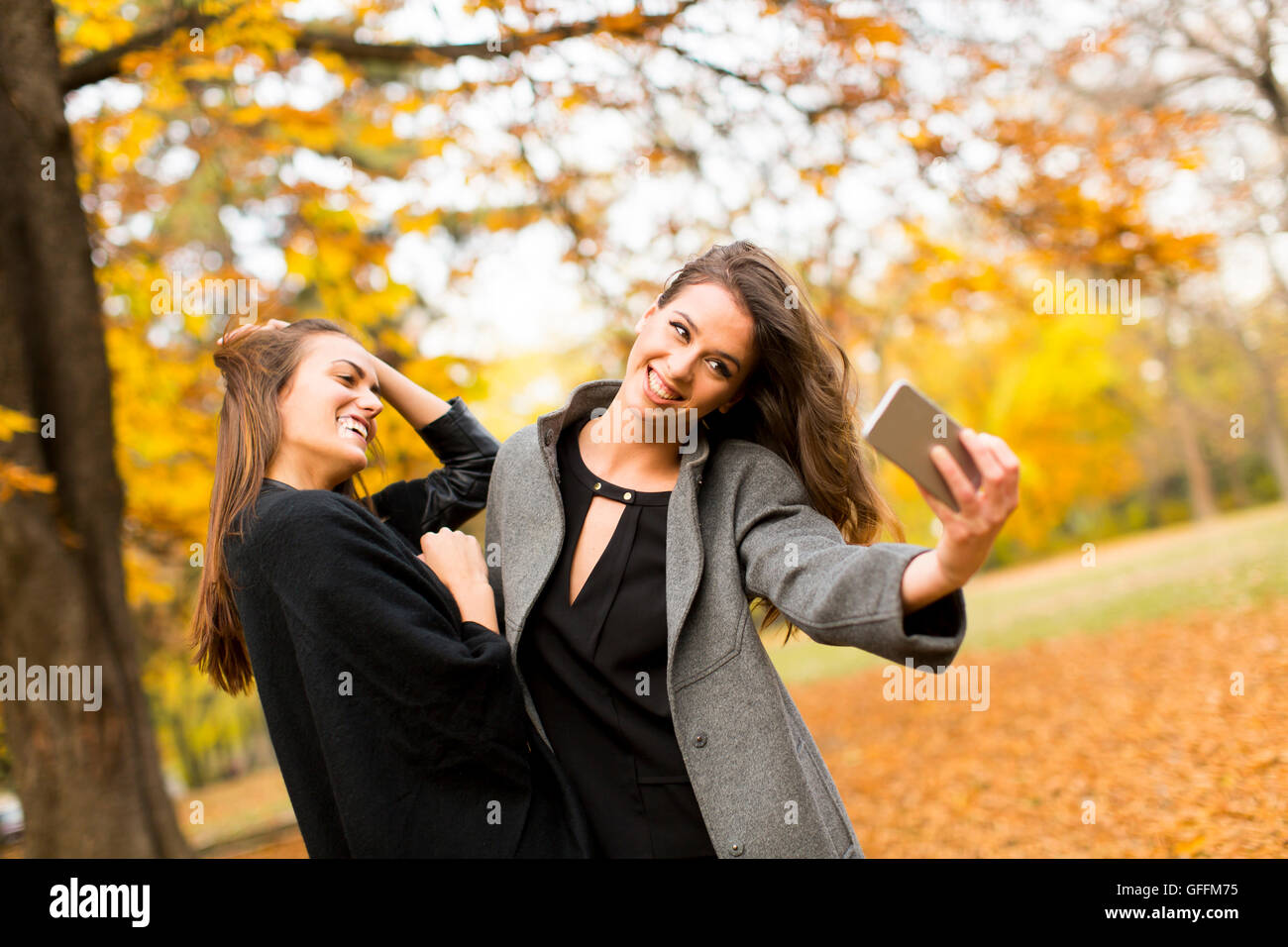 Young women taking selfie with mobile phone in the autumn forest Stock ...