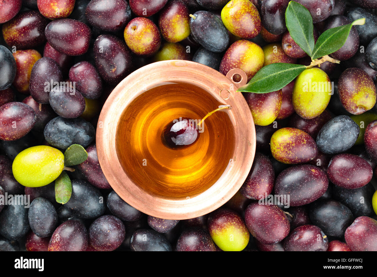 Background of fresh olives and pot with olive oil in the middle Stock
