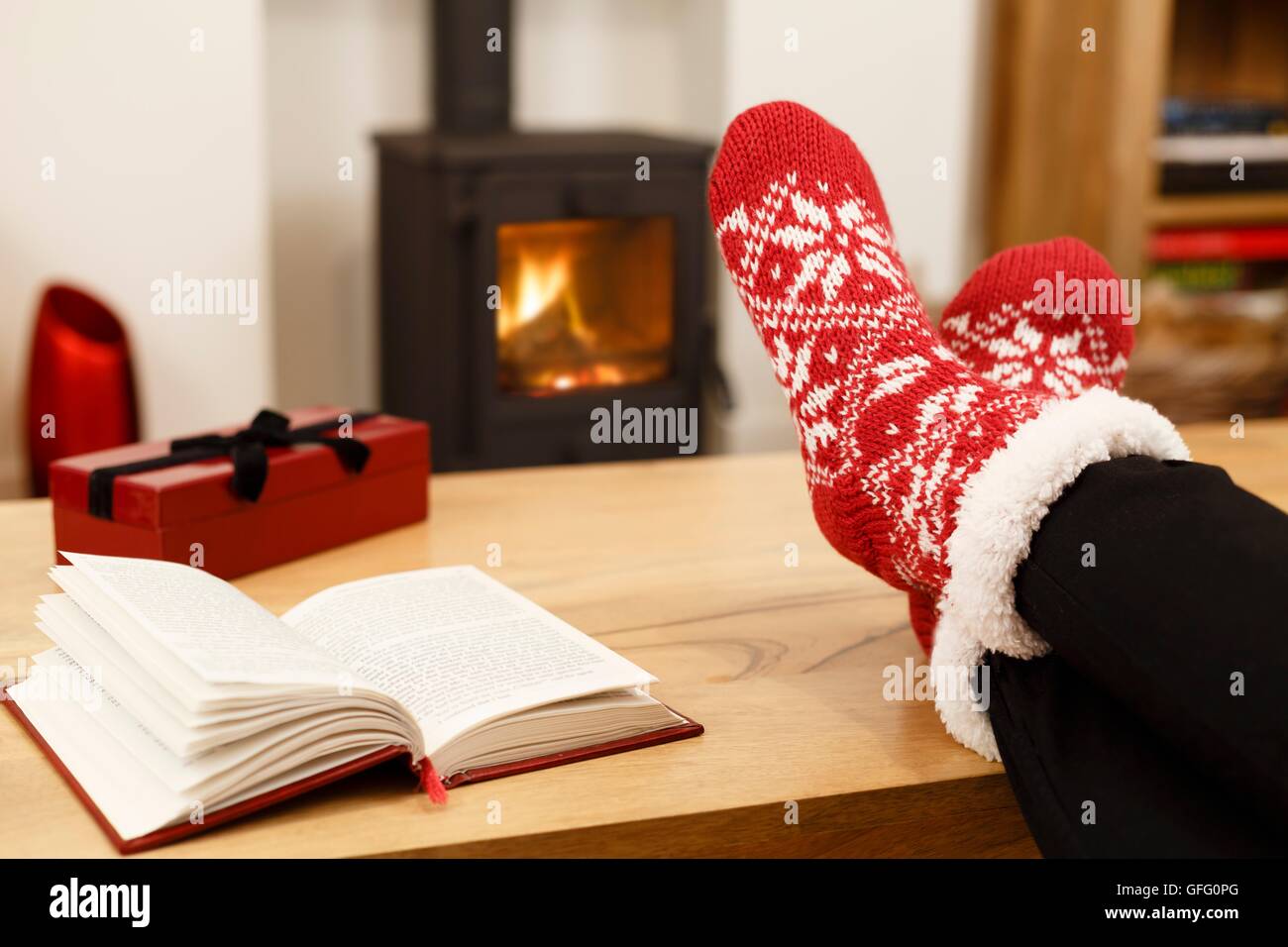 Woman relaxing at home in front of a cozy fire at Christmas Stock Photo