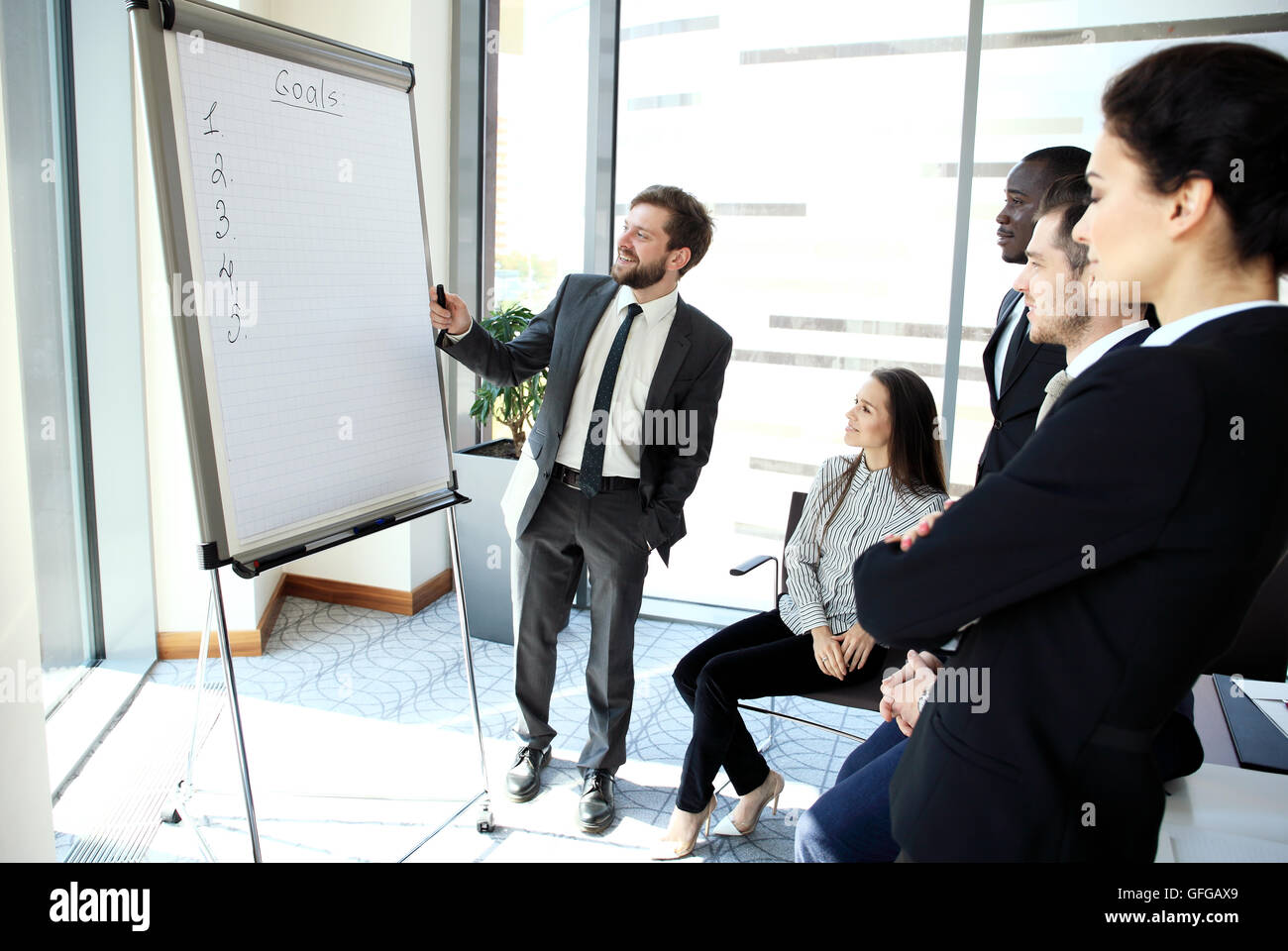 Cheerful businessman discussing new business project with the members of his team Stock Photo