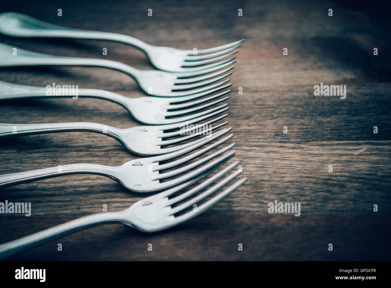 Forks arranged on wooden tabletop Stock Photo